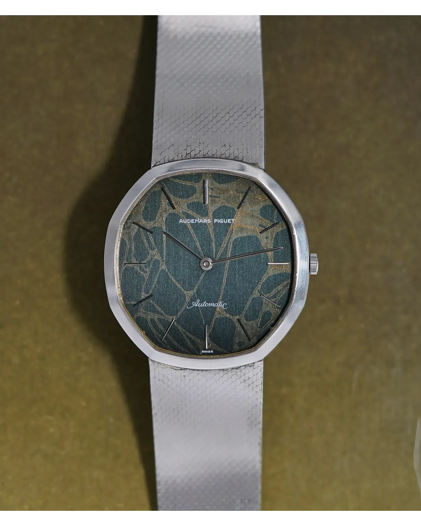 Dial detail of a vintage Audemars Piguet automatic with tropical patina dial on grey textured strap.