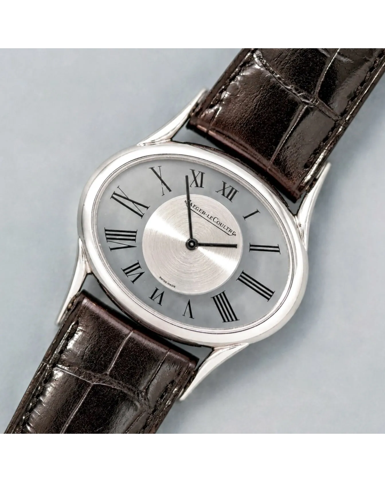 Dial detail of a Jaeger-LeCoultre dress watch with silver Roman numeral dial and brown alligator strap.