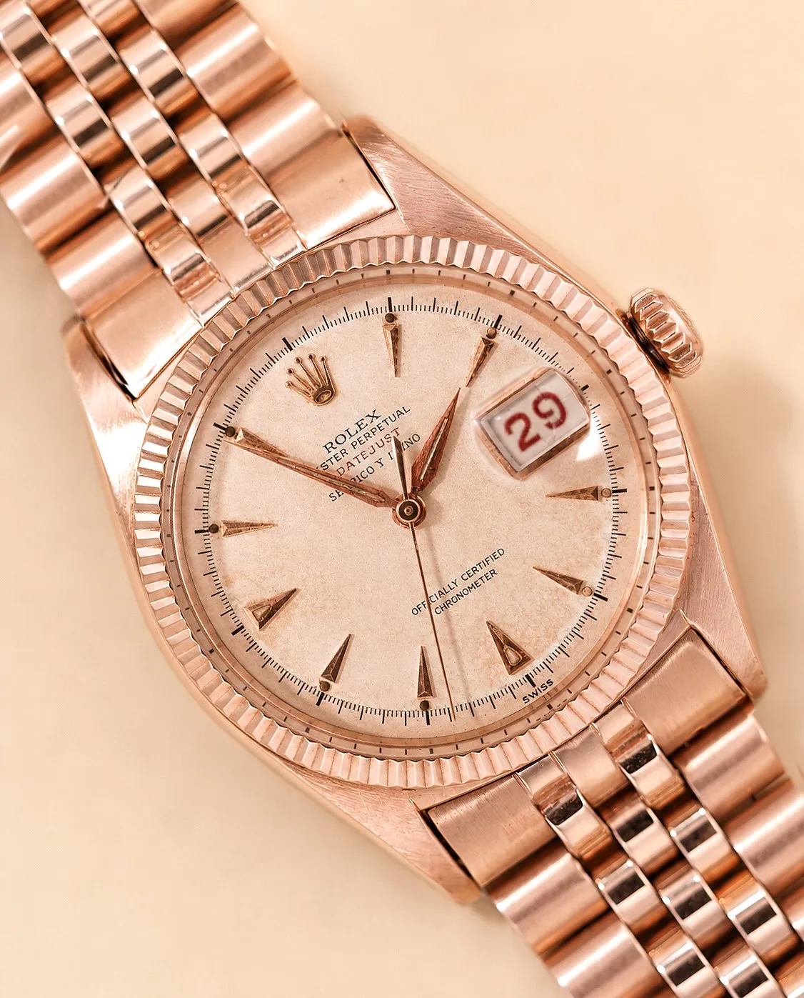 Dial detail of a rose gold Rolex Datejust with fluted bezel, arrowhead indices, and aged champagne dial.