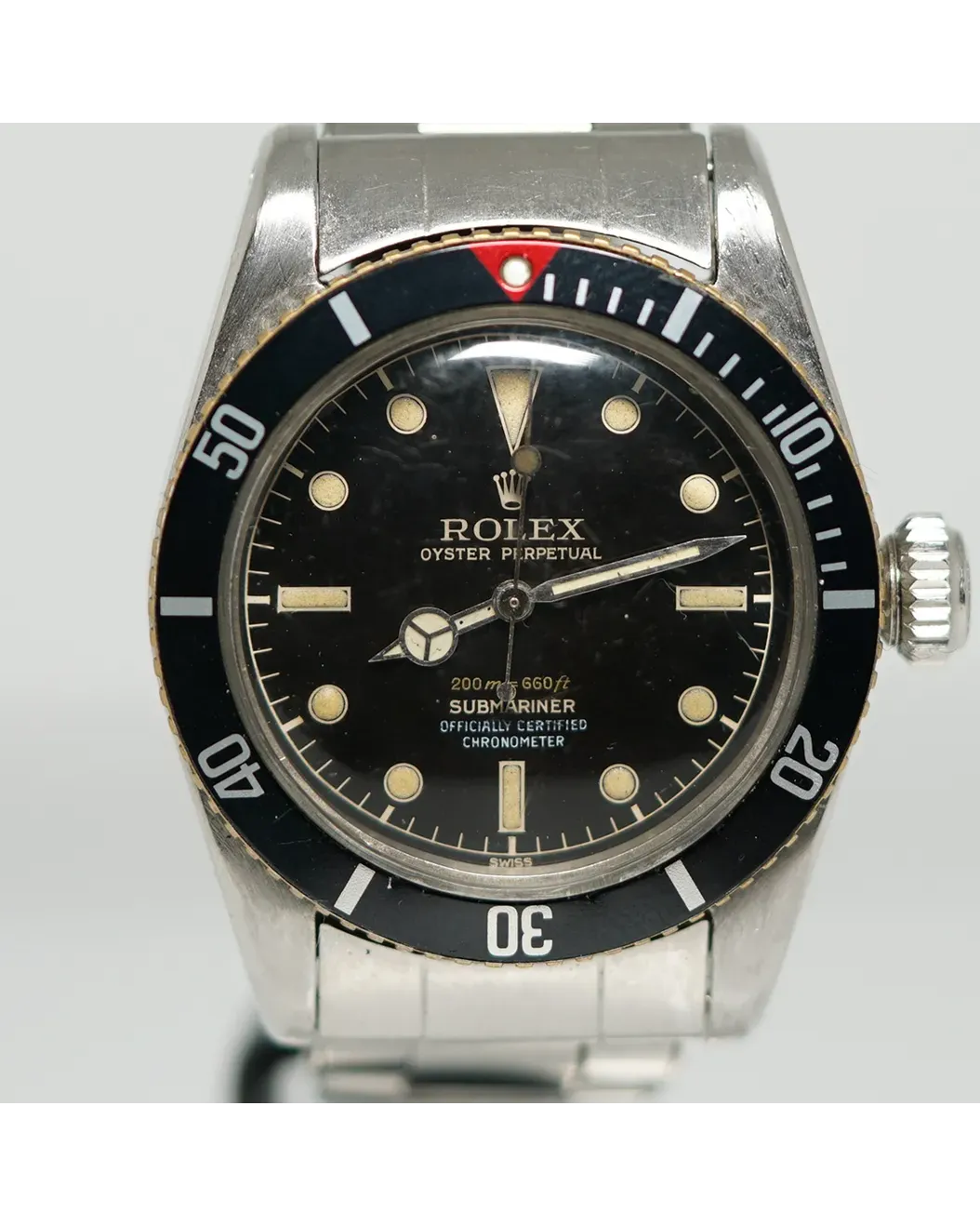 Dial detail of a Rolex Oyster Perpetual Submariner with black gilt dial, patinated luminous markers, and rotating bezel.