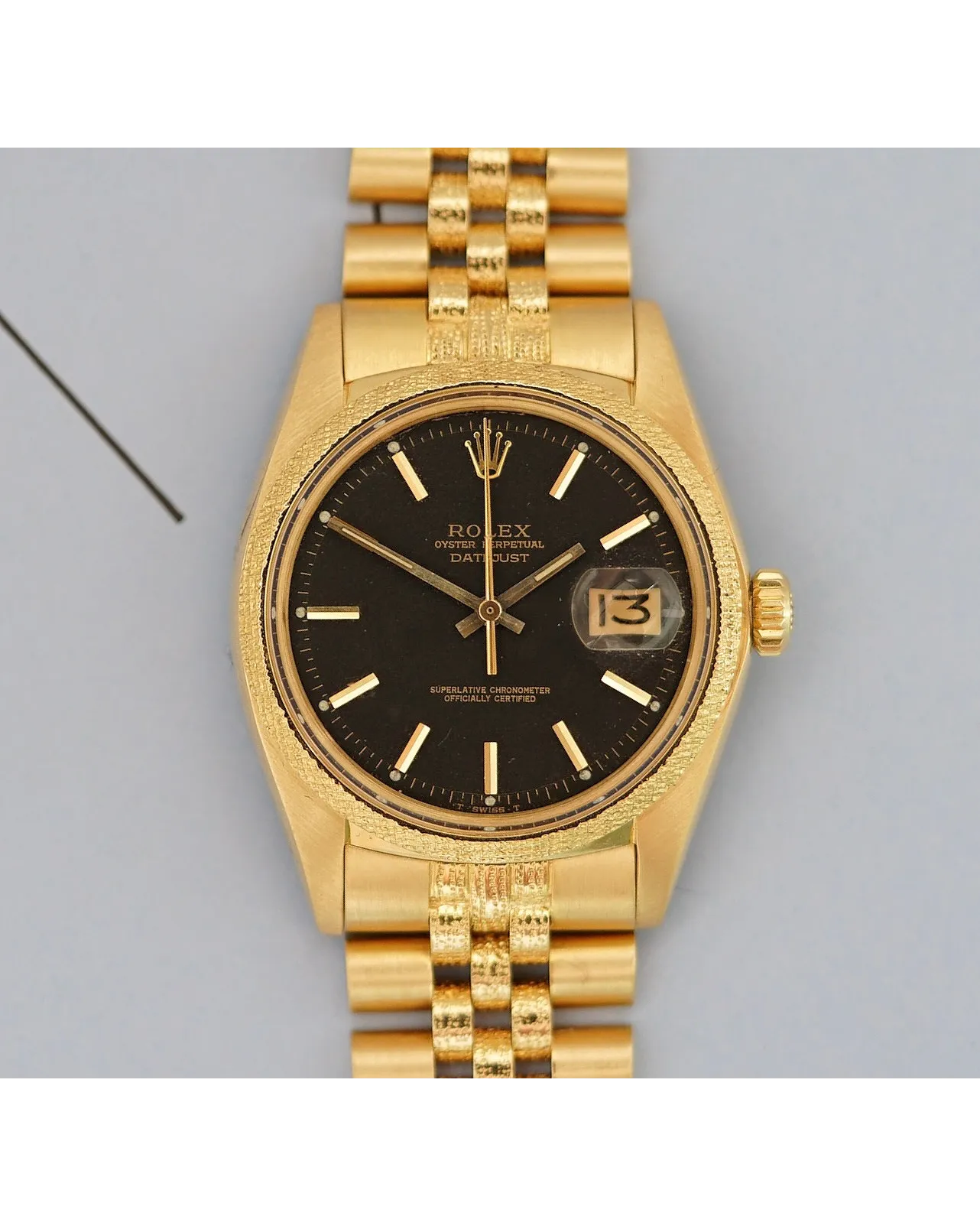 Dial detail of a yellow gold Rolex Oyster Perpetual Datejust with black dial and Jubilee bracelet showing tropical patina.