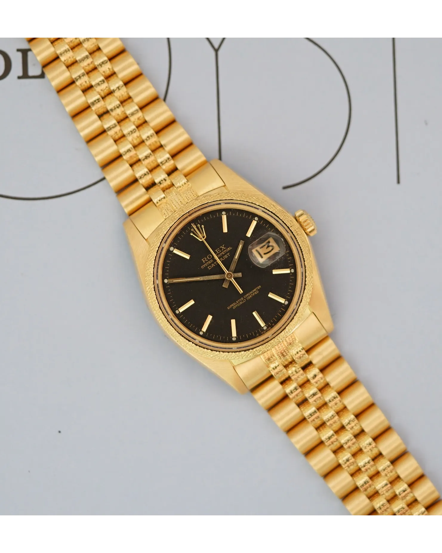 Dial view of a yellow gold Rolex Datejust with black tropical dial on Jubilee bracelet.