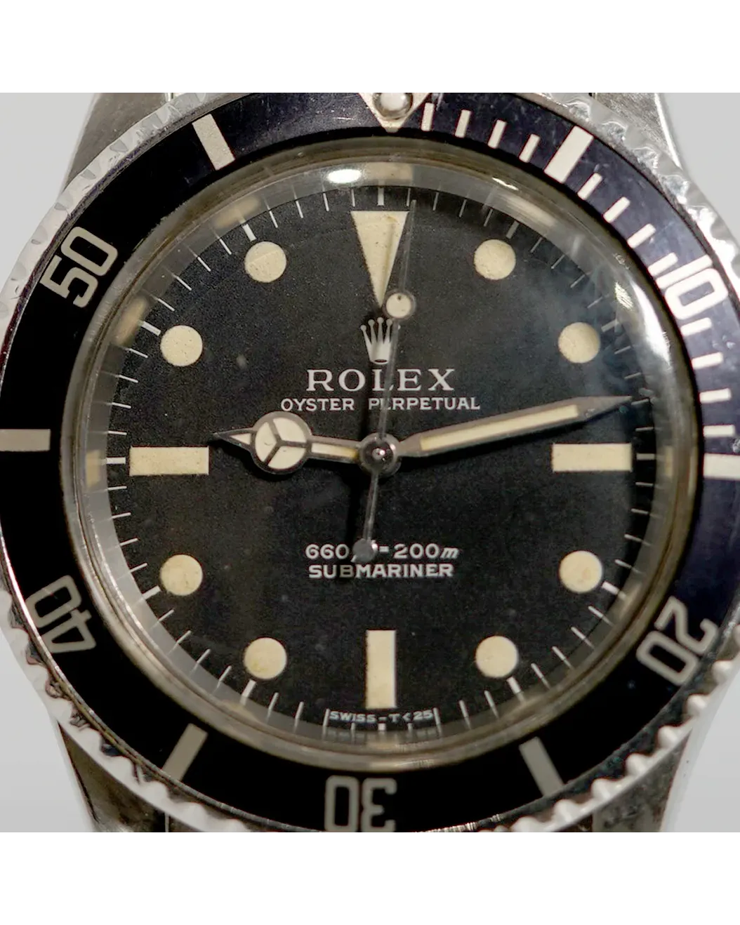 Dial detail of a Rolex Submariner 5513 showing matte black dial, gilt text, and cream patinated luminous markers.