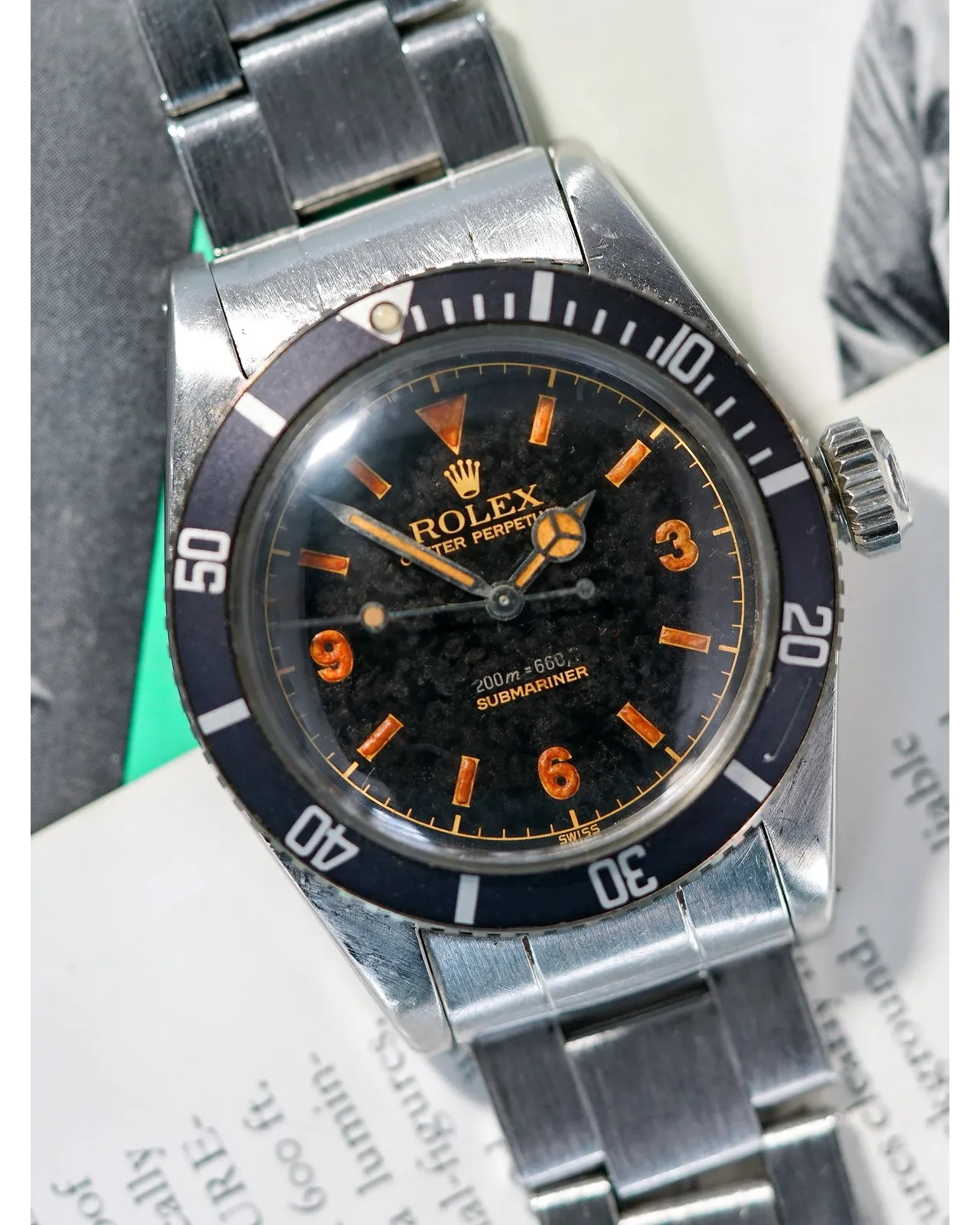Three-quarter view of a vintage Rolex Submariner with tropical gilt dial, orange Explorer numerals, and faded bezel insert.