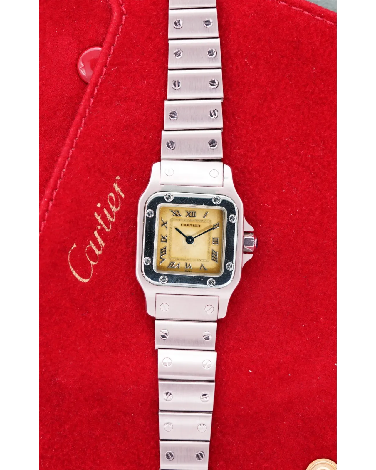Overhead flat-lay of a Cartier Santos Galbée ladies watch with cream dial, Roman numerals, and steel bracelet.