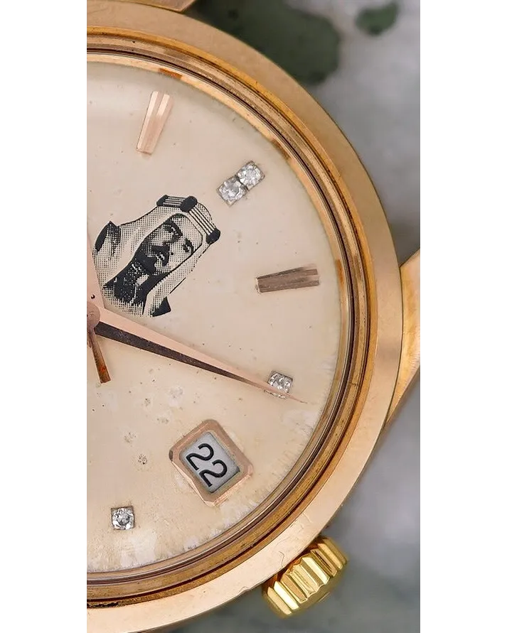 Dial detail of a rose gold watch with champagne dial, applied baton markers, diamonds, and date window at six.
