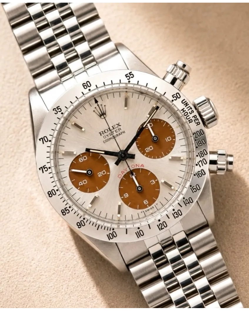 Dial detail of a Rolex Cosmograph Daytona with silver dial, brown subdials, and steel bracelet.