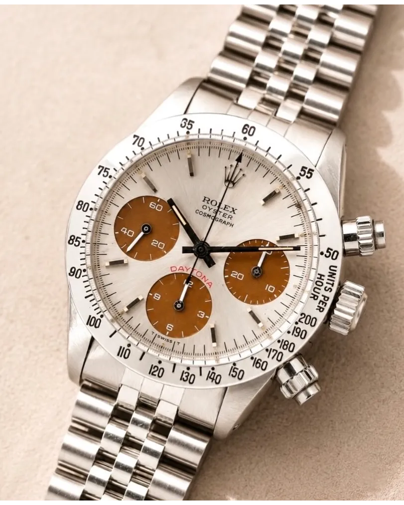 Dial detail of a Rolex Cosmograph Daytona with white dial, brown sub-dials, and Jubilee bracelet.