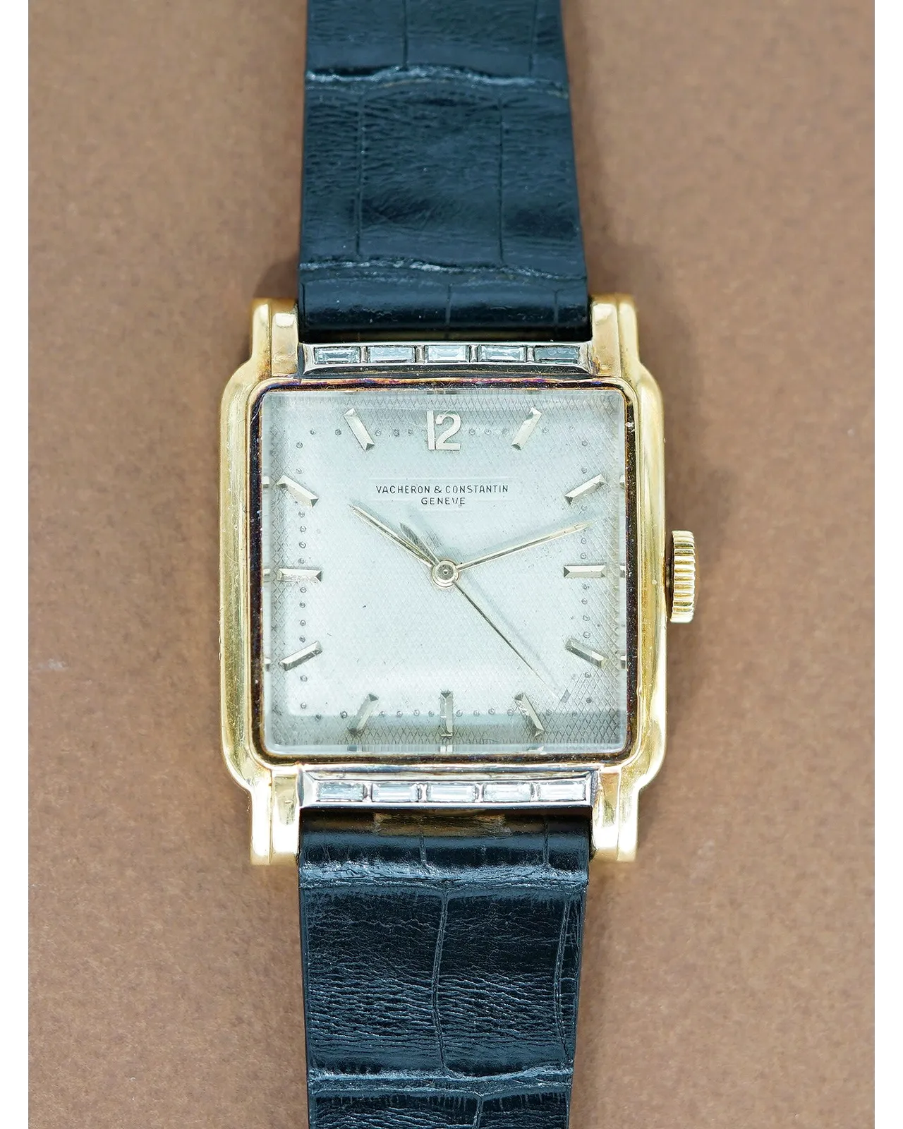 Dial view of a vintage Vacheron & Constantin Genève square gold watch with silvered dial on black crocodile strap.