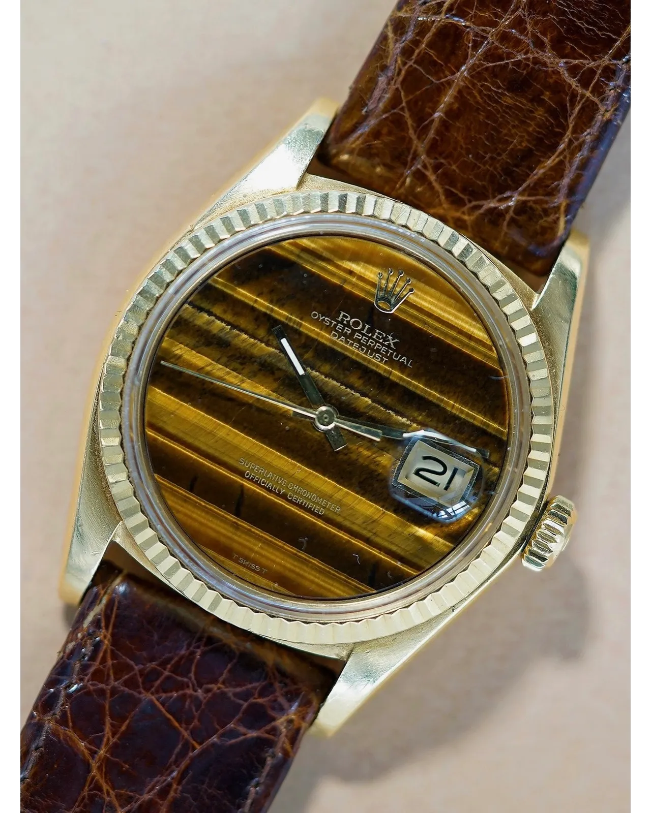 Dial detail of a yellow gold Rolex Oyster Perpetual Datejust with tiger's eye stone dial on brown leather strap.