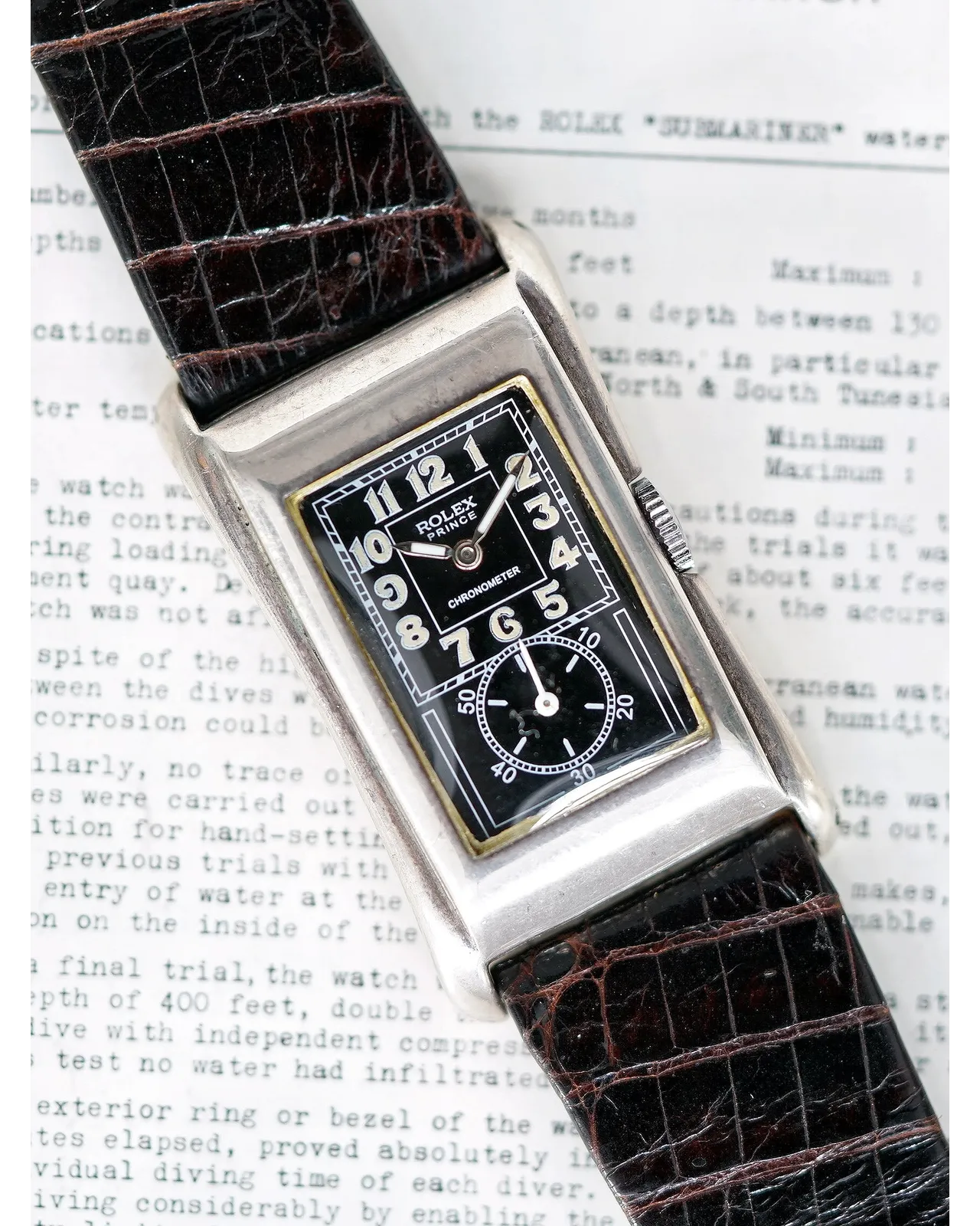 Dial detail of a rectangular Rolex chronometer with black dial, Arabic numerals, and subsidiary seconds on crocodile strap.