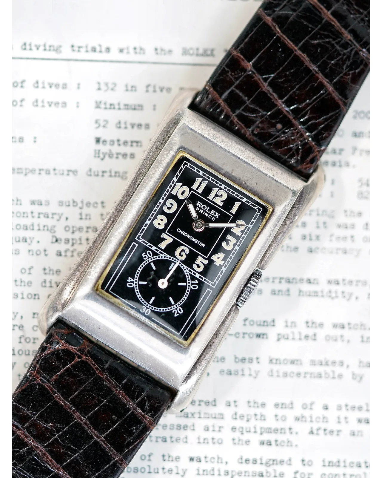 Dial detail of a rectangular Rolex Prince Chronometer with black Art Deco dial and brown crocodile strap.