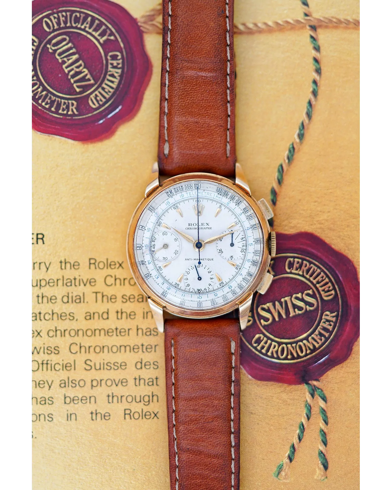 Dial view of a vintage Rolex chronograph in rose gold with white multi-scale dial on brown leather strap.